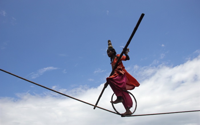 A tightrope walker performs on a rope while holding a balancing pole during a performance at Puri